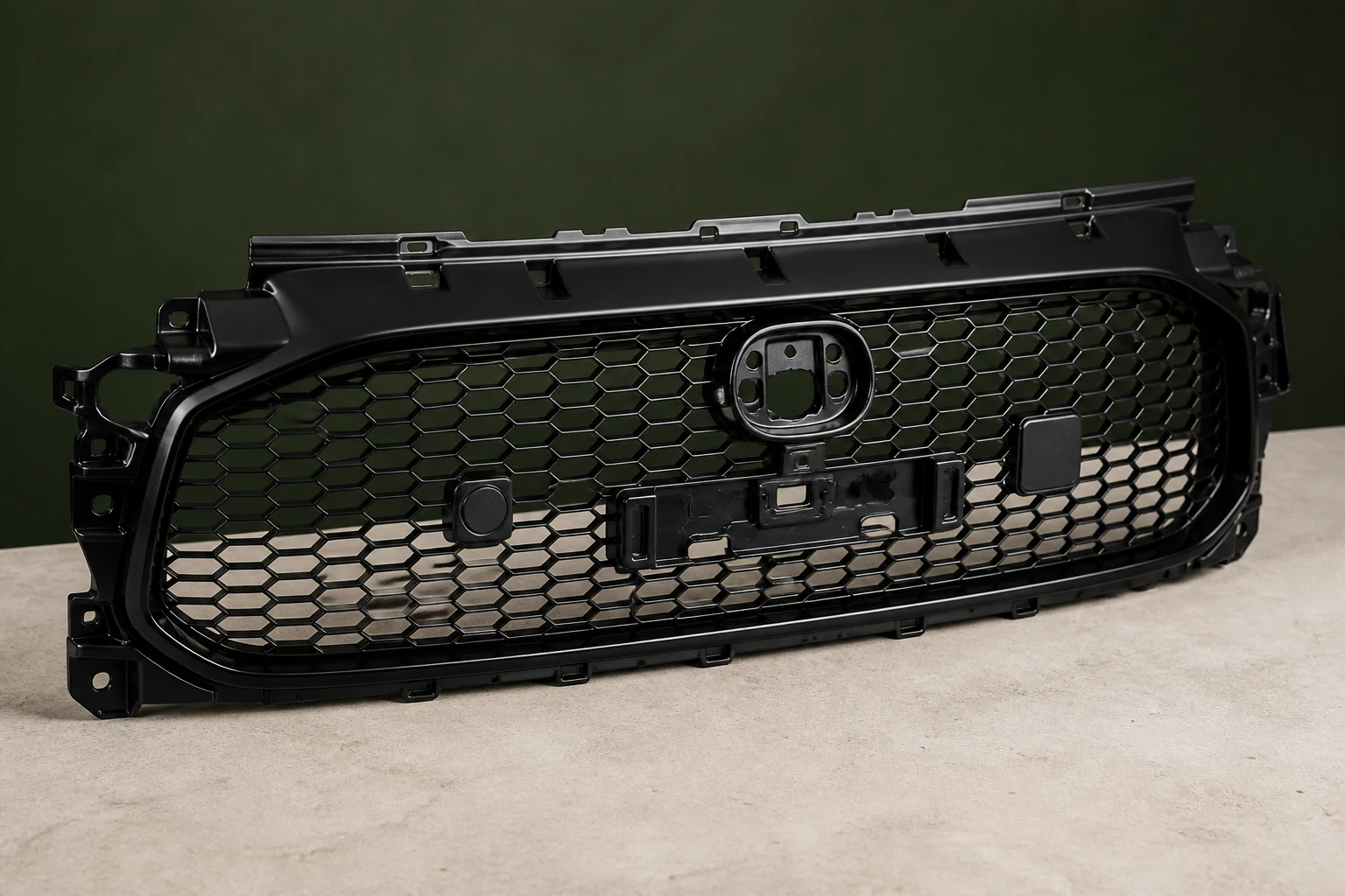 Unbranded black automotive radiator grille with honeycomb mesh, perimeter frame, mounting tabs and sensor openings