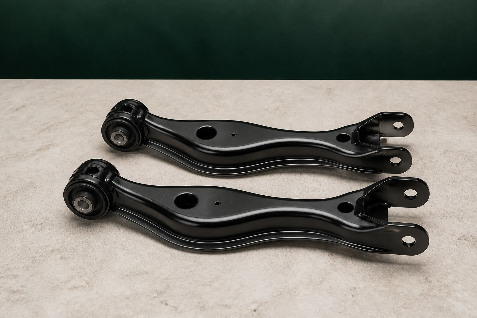 Pair of unbranded rear suspension control arms with pressed rubber bushings, formed steel bodies and mounting eyes